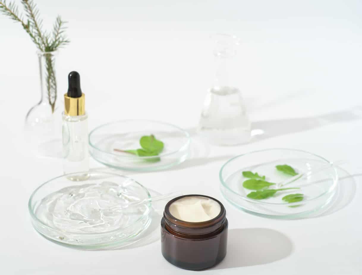 Vegan cosmetic cream and laboratory petri dishes on a lab table and glassware